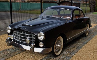 A black 1950s classic coupé on cobblestones, photographed for an online car auction